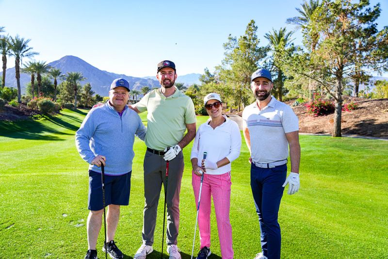 4 people with golf clubs ready to tee off