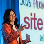 Krysteena Meredith, SITE SoCal’s 2025 President, wearing an orange jacket, speaks on stage with "SITE" visible on the presentation backdrop.