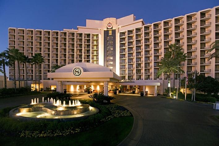 A modern, multi-story hotel entrance labeled "Century Plaza," with balconies on each floor and a covered driveway.