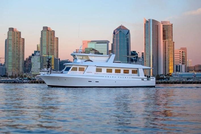 The Zolna Yachts’ Nerissa on calm water at sunset with San Diego skyline in background..